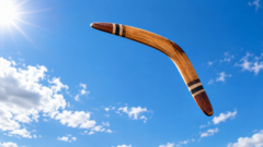 Un boomerang di legno in volo contro un cielo azzurro e terso.