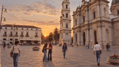 Piazza di Pompei al tramonto, ricostruita negli anni Settanta, con giovani studenti che camminano e si scambiano appunti prima dell’esame di maturità.